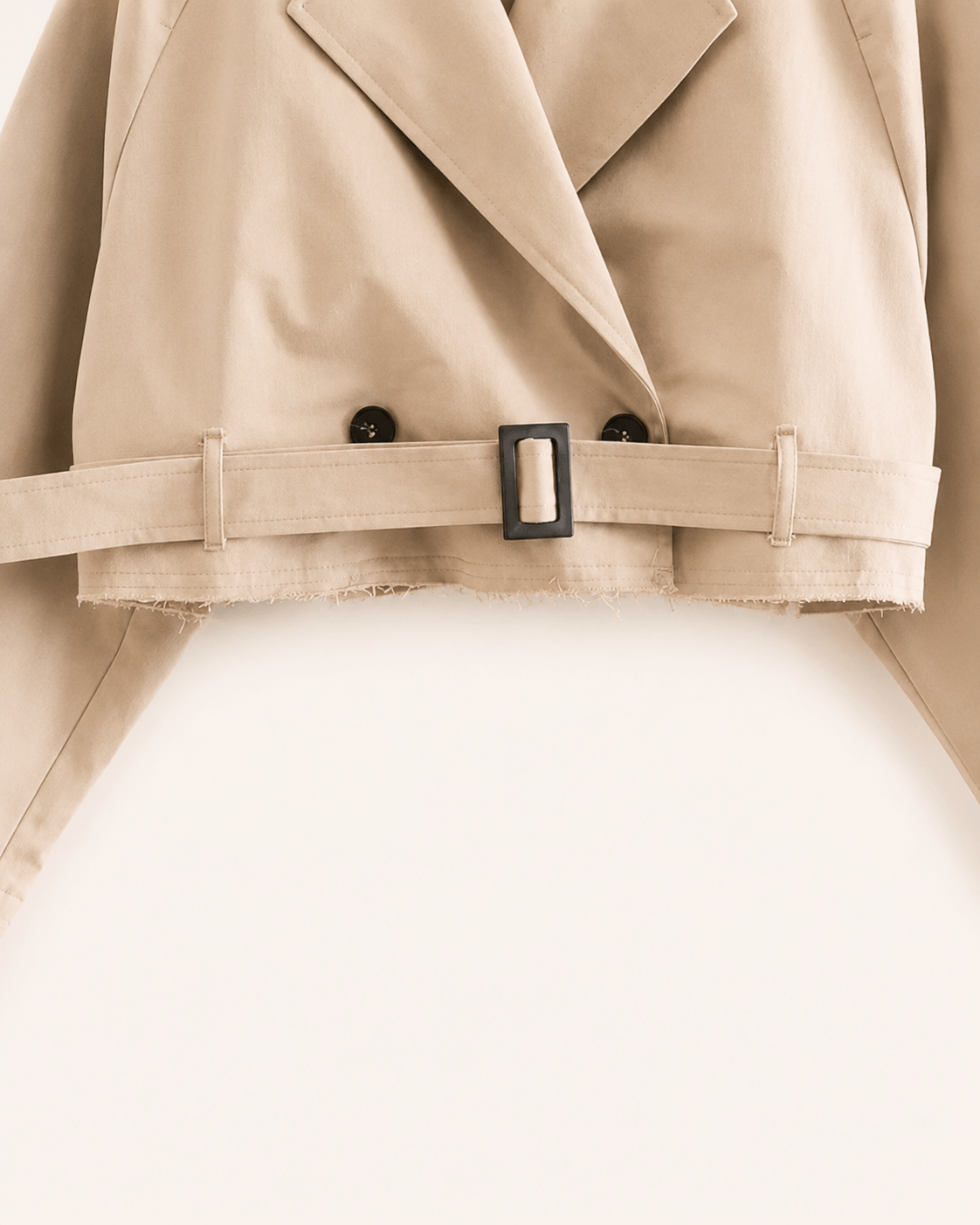 Détail de la ceinture à boucle rectangulaire mate et de l'ourlet effiloché, veste trench camel