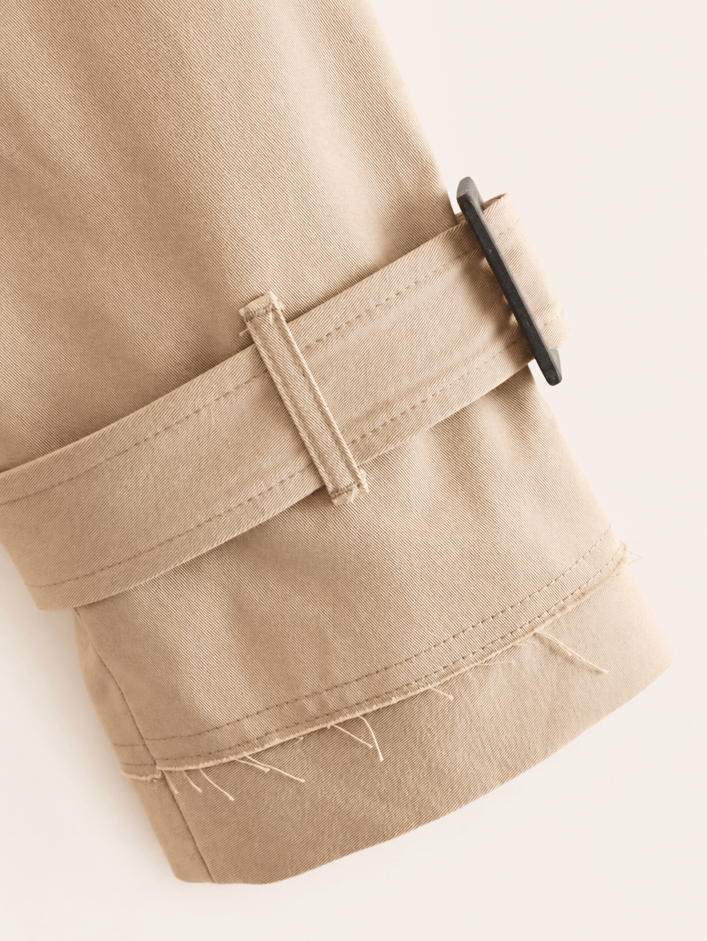 Bas de manche de la veste trench camel, patte de serrage à boucle et ourlet à bord franc