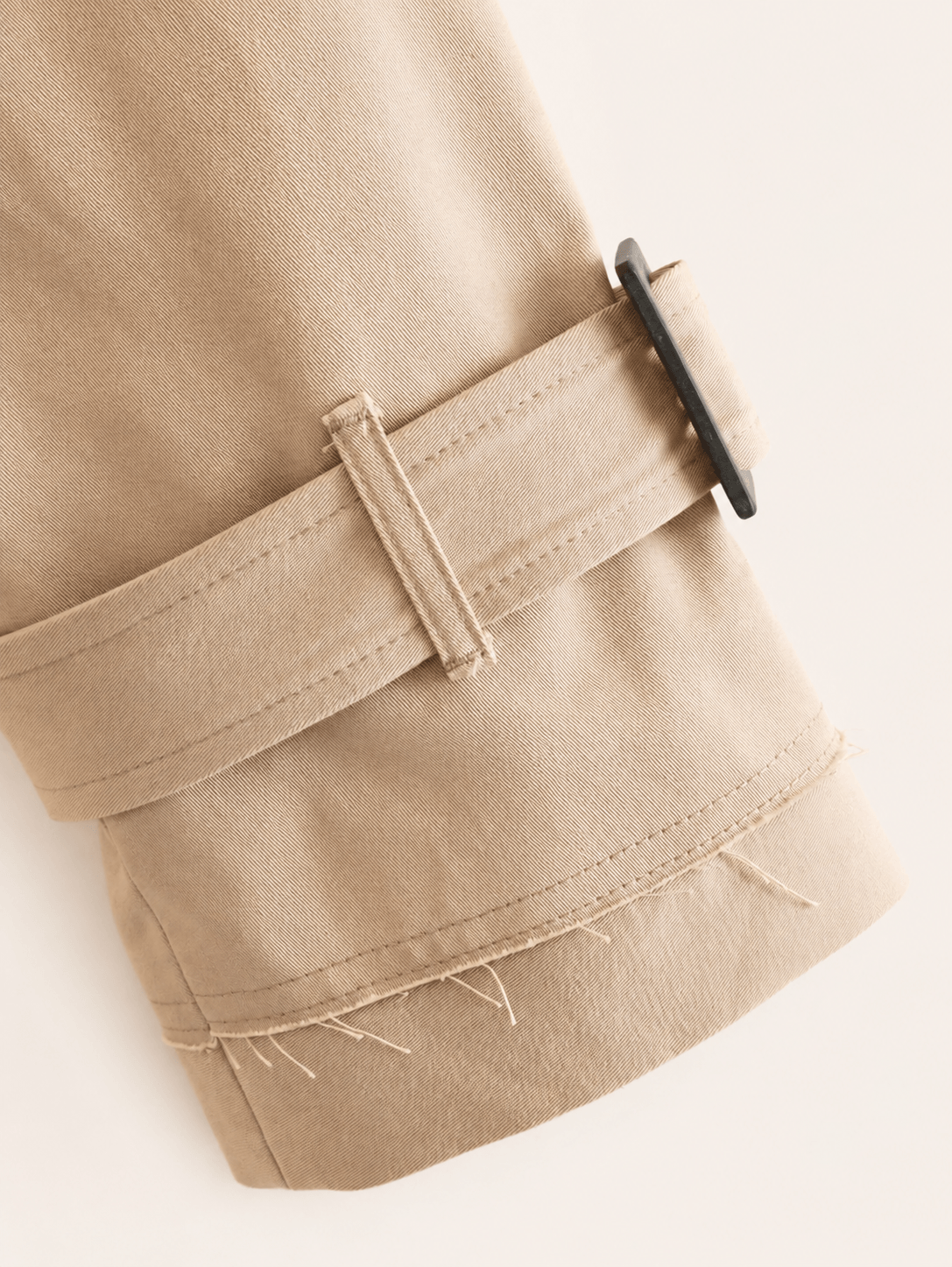 Bas de manche de la veste trench camel, patte de serrage à boucle et ourlet à bord franc
